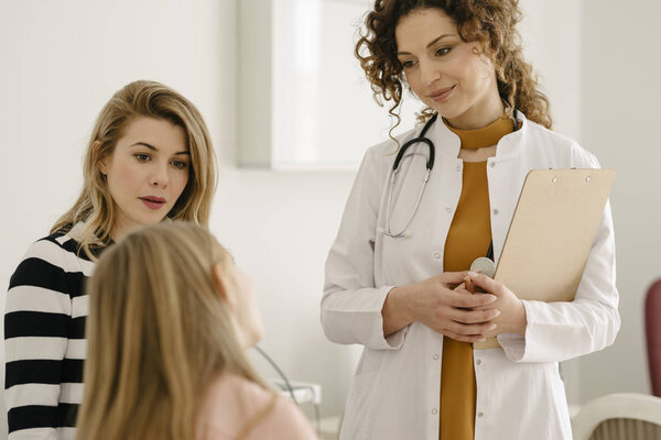 Красивая женщина-педиатр разговаривает с родителями и детьми
.