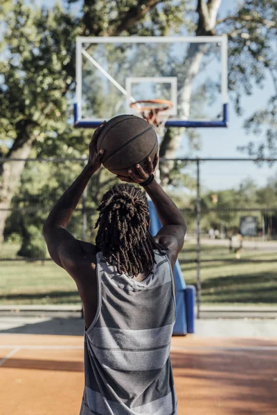 Back view of African basketball player standing on outdoor court.