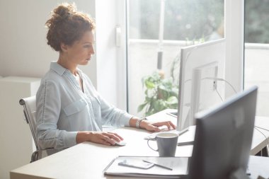 Bir fare ve klavye modern ofis alanı kullanan bir masaüstü bilgisayarda çalışan genç iş kadını.