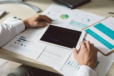 Eller yukarıda onun grafikler ve notları tablet modern ofis alanı kullanma genç işadamı.