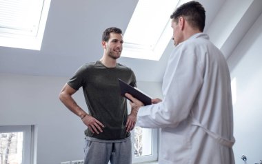 Genç yakışıklı beyaz hastaya onun doktor fizik tedavi tavsiye almak.