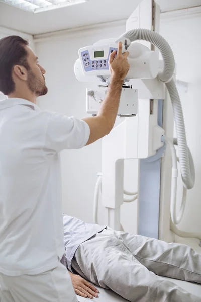 Young medical technician operating an X-ray machine in a clinic.