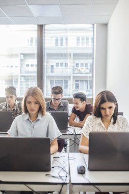 Grup modern sınıf oturma ve dizüstü bilgisayarlarda yazmaya lise öğrenci.