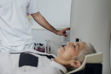 Onun hasta Ct tarayıcı yatakta yatarken Ct tarayıcı düğmelere basarak tanınmaz halde tıbbi teknisyen.