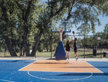 Açık sahada basketbol oynayan iki genç oyuncular.