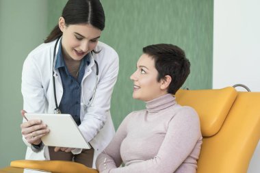 Neşeli gülümseyen kadın doktor hastasını hastanede konuşurken.