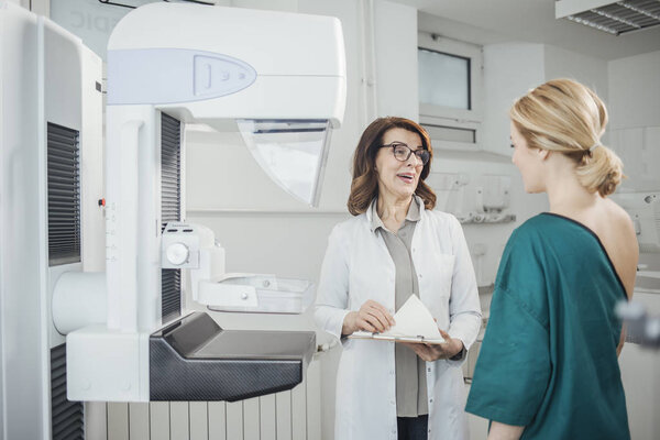 Woman oncologist talking with her patient on mammography examination.