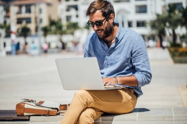 Bankta oturan ve onun dizüstü bilgisayarda çalışan yakışıklı beyaz adam serbest meslek.