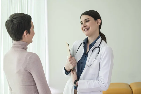 漂亮的白种女人医生微笑着和她的病人在医院交谈 — 图库照片