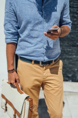 Açık havada duran ve cep telefonundan yazarak unrecognisable işadamı.