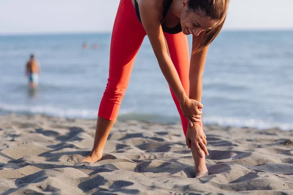 砂浜のビーチでストレッチ運動をやってかなり白人女性 — ストック写真