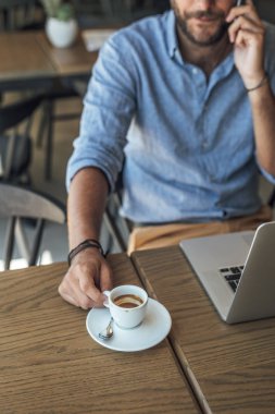Kahve dükkanında oturmuş ve cep telefonuyla konuşurken unrecognisable işadamı.