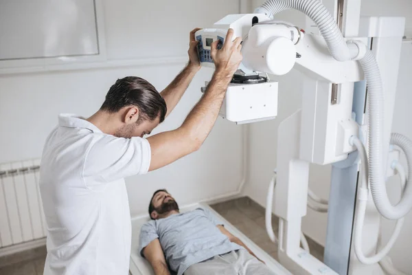 Unga Medicinska Tekniker Verksamma Röntgenapparat Medan Hans Patienten Ligger Sängen — Stockfoto