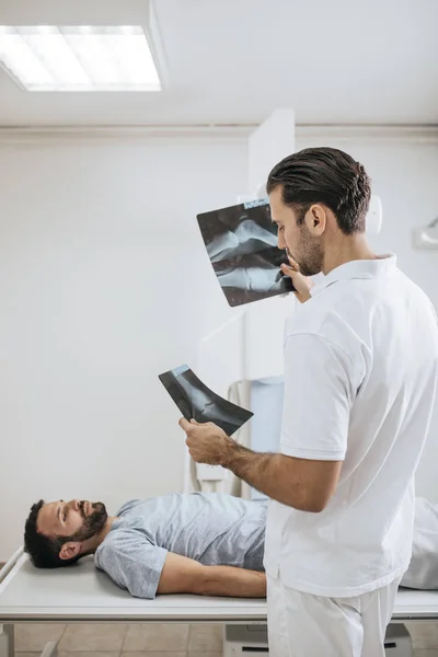 Молодий Медичний Технік Вивчає Рентгенівські Фільми Його Пацієнт Лежить Ліжку — стокове фото