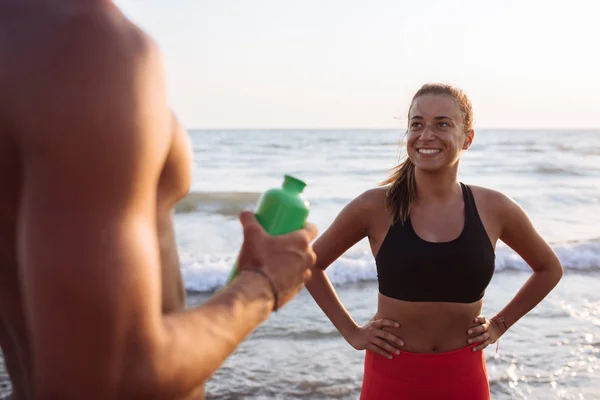 Beautiful smiling woman enjoying exercising by the beach with her boyfriend.