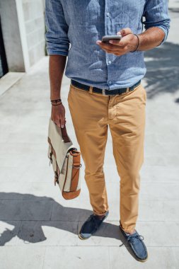 Açık havada duran ve cep telefonundan yazarak unrecognisable işadamı.