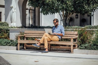 Açık havada oturma ve çalışma onun laptopunda yakışıklı beyaz işadamı serbest meslek.