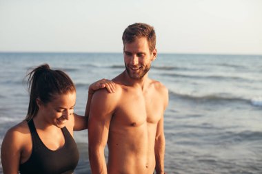 Yaz aylarında kumsalda yürüyen genç mutlu çift.