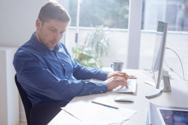Genç işadamı modern ofis alanı, bir masaüstü bilgisayarda çalışırken not alma.