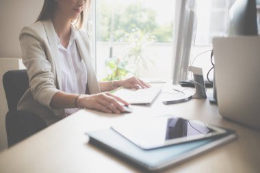 Bir fare ve klavye modern ofis alanı kullanan bir masaüstü bilgisayarda çalışan genç iş kadını.