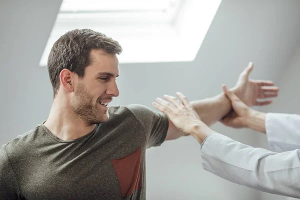 Jovem Bonito Homem Caucasiano Esticando Braço Com Seu Médico Ajudando — Fotografia de Stock