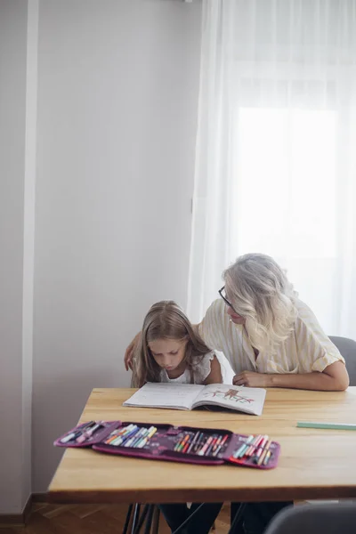 Söt Blond Skolflicka Lära Sig Läsa Med Mamman Att Hjälpa — Stockfoto