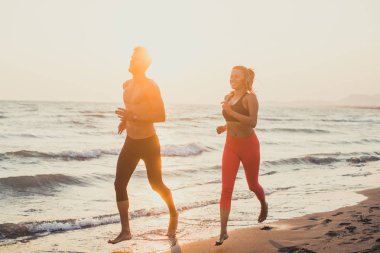 Yakışıklı beyaz adam ve kumsalda günbatımında çalışan güzel kadın.
