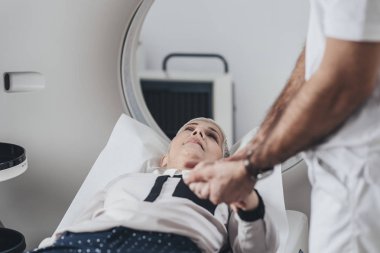 Tıbbi teknisyen Tc tarayıcı yatakta yatıyordu hasta elini tutarak.