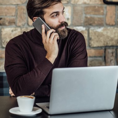 Kahve dükkanında cep telefonuyla konuşurken yakışıklı işadamı serbest meslek.