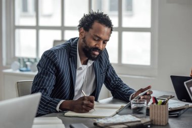 Bir tablet bir elinde tutarken notlar alarak iş adamı.
