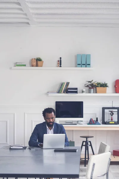 近代的なオフィス スペースでノート パソコンの前でメモを取るビジネスマン — ストック写真