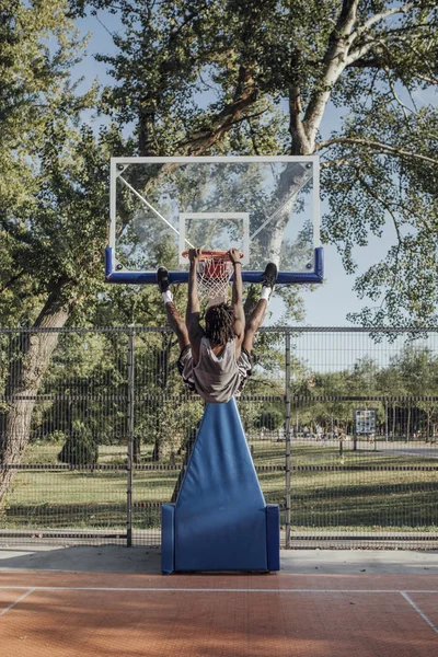 年轻的非洲裔美国人挂在室外篮球场上的篮球圈 — 图库照片
