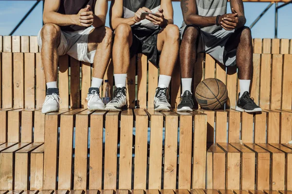 Nohy Tří Mladých Mužů Sedí Venkovní Dřevěné Basketbal Soudu Tribuny — Stock fotografie