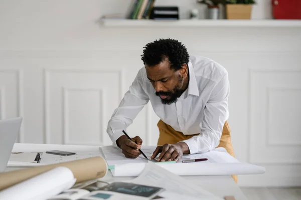 Ein Seriöser Afrikanischer Architekt Zeichnet Seinem Büro Baupläne Stockbild