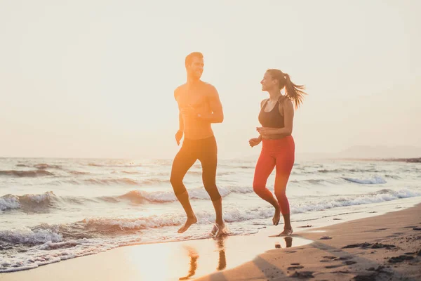 Schöner Kaukasischer Mann Und Schöne Frau Die Bei Sonnenuntergang Sandstrand lizenzfreie Stockfotos