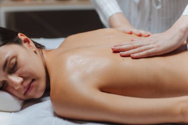 genç kadının bir spa merkezinde bir sırt masajı.