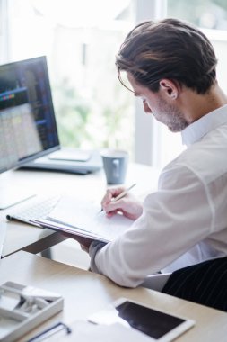 Genç işadamı modern ofis alanı ise, bir masaüstü bilgisayarda çalışırken not alma.