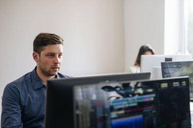 Modern ofis alanı, masaüstü bilgisayarlarında çalışan genç iş adamları.