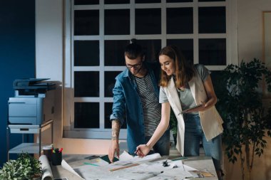 İki genç Kafkas mimarlar, bir erkek ve bir kadın, birlikte geceleri bir ofiste çalışırken tablet kullanma.