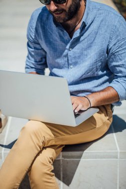 Bankta oturan ve onun dizüstü bilgisayarda çalışan yakışıklı beyaz adam serbest meslek.