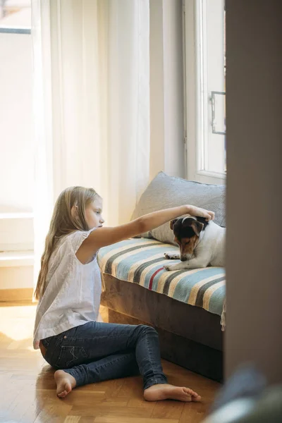 自宅に彼女の犬のペットを抱きしめるかなりブロンドの女の子 — ストック写真