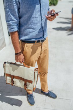 Açık havada duran ve cep telefonundan yazarak unrecognisable işadamı.