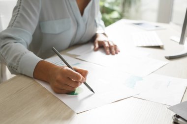 Genç işkadını grafikler masaüstü bilgisayar başında modern ofis alanı önünde incelenmesi.