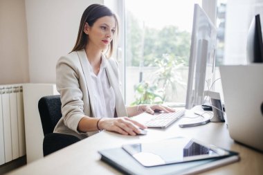 Bir fare ve klavye modern ofis alanı kullanan bir masaüstü bilgisayarda çalışan genç iş kadını.
