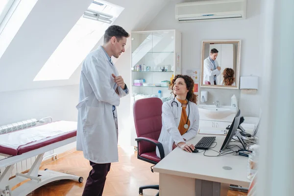 Two young Caucasian physicians working in a modern medical office.