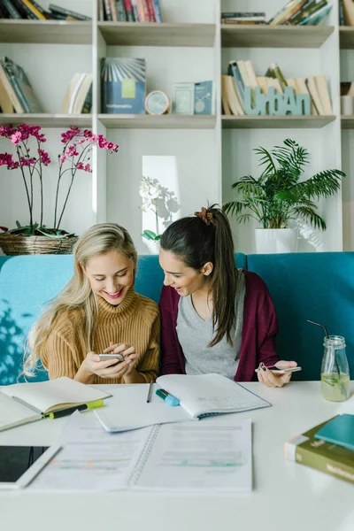 Duas Meninas Bonitas Estudantes Universitários Usando Telefones Inteligentes Enquanto Estudam — Fotografia de Stock