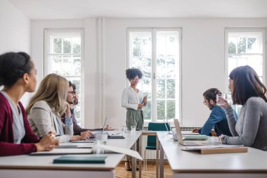Genç Afrika işkadını modern ofis onun arkadaşları için sunuyu yapma.
