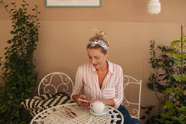 Красивая Белая Женщина Пользуясь Мобильным Телефоном Пьет Кофе Террасе — стоковое фото