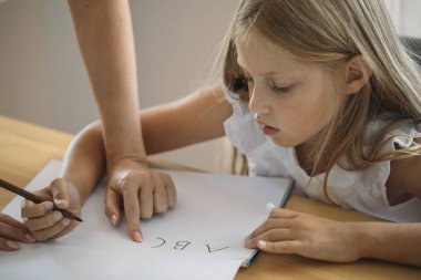 Sevimli sarışın kız öğrenci annesi yardım mektup yazmak öğrenme.