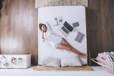 Genel gider bir yatakta yatarken cep telefonu konuşurken çok gülümseyen kafkas kadın fotoğrafı.